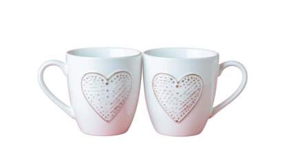 Two white mugs with heart designs are positioned closely together in a centered composition studio shot on white and transparent