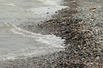 The surf line of a sea pebble beach, a rib-like wave of sea pebbles