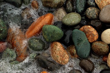 Background, texture of sea pebbles in the sea foam of the surf