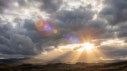 Dramatic sky with golden sun rays breaking through dark stormy clouds over rolling hills