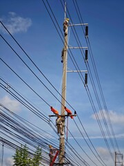 Team of electrical lineman workers climbing concrete pole with safety spikes to replace insulators...