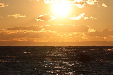 Clouds and waves shining in the setting sun