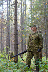 A hunter stands in a coniferous forest