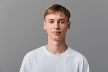 Man in white t shirt looking at camera, simple studio setup with neutral gray background, clean...