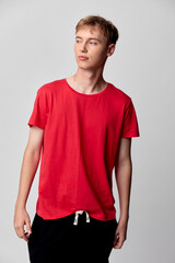 Fototapeta premium Red shirt, male model, casual wear, studio shot, fashion, young adult, relaxed pose, everyday clothing, minimal styling, bright backdrop, clean aesthetic for stock use