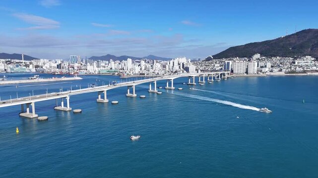 Drone footage captured during daytime showing coastal city bridge over turquoise sea under clear weather conditions. Aerial wide shot suitable for travel tourism urban lifestyle transportation and bac