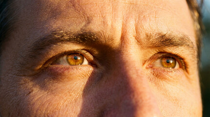 Sunlight illuminates a man's focused brown eyes