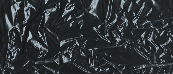 Wrinkled plastic wrap texture on a black background. Cellophane package wallpaper