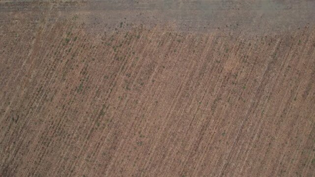 Slow aerial reveal identifies the dark, saturated furrows of a plowed field in the Po Valley, where a week of heavy rain has transformed the silty clay substrate into a waterlogged mosaic PC Italy