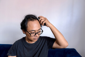 A man drops serum using a spray on his scalp in the bald area, hair loss treatment, Concept of baldness treatment or hair restoration