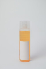 Single orange cosmetic bottle with a blank white label and transparent cap, isolated on a white background. Perfect for beauty branding mockups and skincare product labels