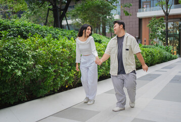 Captured in motion,  Asian shoppers walk enthusiastically through the outdoor grounds of a shopping center. They hold assorted retail bags, evincing joy following their purchasing activities