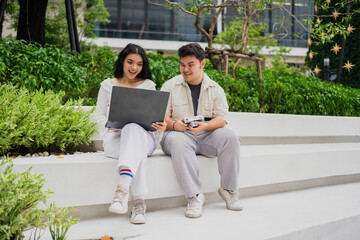 Enjoying a sunny day, two female Asian friends stroll through an outdoor shopping district. The image captures them holding several shopping bags and smiling broadly, highlighting a pleasant consumer 