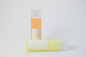 Two plastic cosmetic bottles with blank labels, one standing and one lying down, isolated on white background. Perfect for skincare branding, beauty products, or medical mockups