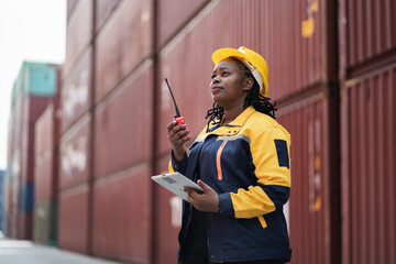 Portrait African woman logistics workers use notebook computer and walkie talkie checking container