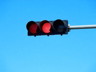 Traffic light with red signal against blue sky