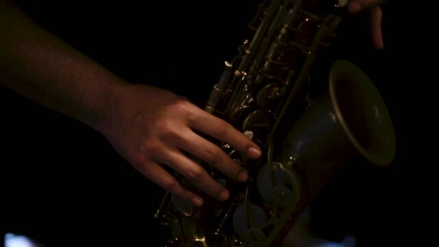 A detailed close-up of a male musician&rsquo;s hand playing a golden saxophone during a jazz rehearsal. The image captures the warmth of brass tones and the texture of the instrument, highlighting passion, 