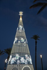 A large illuminated Christmas tree with palm trees and a Bethlehem star on top
