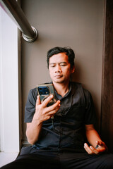 Focused Man Engaged with Mobile Phone Screen While Sitting Indoors
