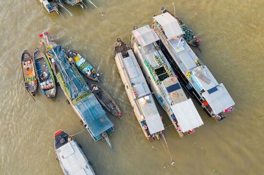 Overhead view shows a cluster of vendor boats loaded with fresh fruits and vegetables at Cai Rang floating market in Can Tho, Mekong Delta, southern Vietnam. The scene features covered vessels