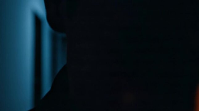 A close-up shot of a person's face with a menacing grin in a dark room, conveying a sense of suspense and intrigue.