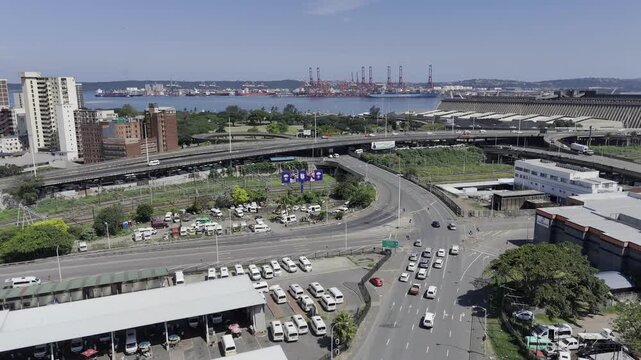 Drone lowers from view of harbor, Albert Park, railroad tracks, and taxi stand down to King Dinuzulu Park on sunny day in Berea, Durban, South Africa