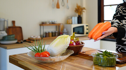 woman and fresh carrots on kitchen table with organic produce, happiness and nutrition for diet,...