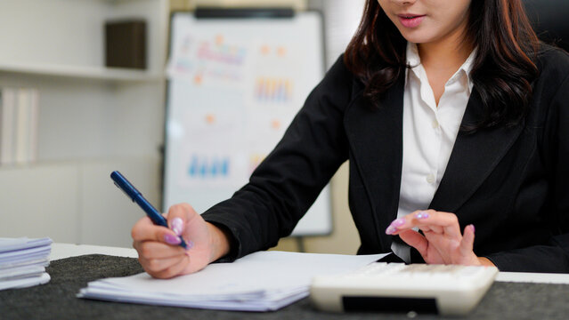 businesswoman using a calculator to calculate the numbers for financial document, finance accounting concept - Powered by Adobe