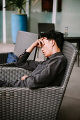 Young Man Feeling Stressed and Tired in a Cafe