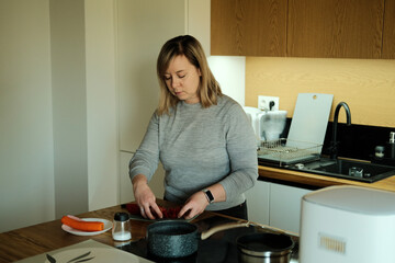 Woman prepares fresh vegetables on kitchen island. Home cooked meals, culinary education, hobby cooking.