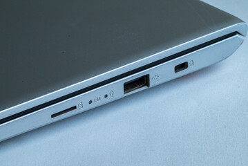 Close-up view of a silver laptop side panel showing various ports including USB, card reader, audio jack, and security lock slot.