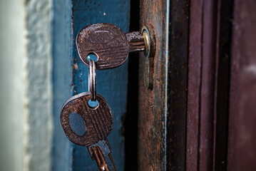 Close-up of an old rusty key in a weathered metal door lock.