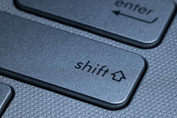 Closed macro shot of the shift key on a computer keyboard with a textured surface and a modern gray color.