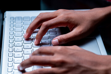 A person's hands are typing on a laptop keyboard.