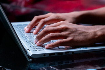 A person's hands are typing on a laptop keyboard.