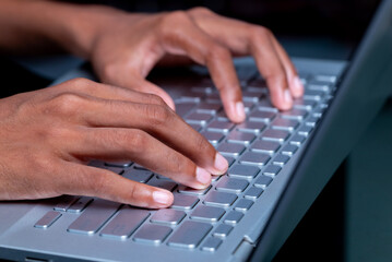A person's hands are typing on a laptop keyboard.