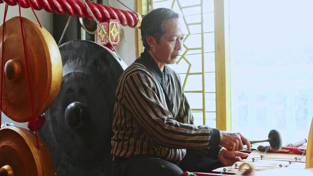 Indonesian musician playing traditional Javanese gamelan instrument