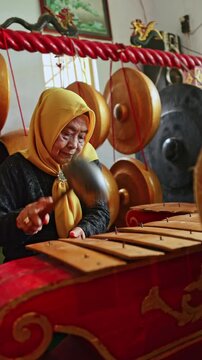 Elderly indonesian musician playing traditional gamelan music