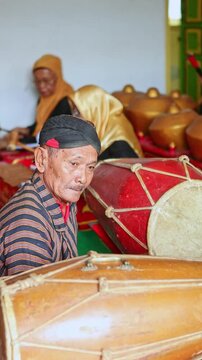 Elderly man playing kendang in a Javanese gamelan orchestra