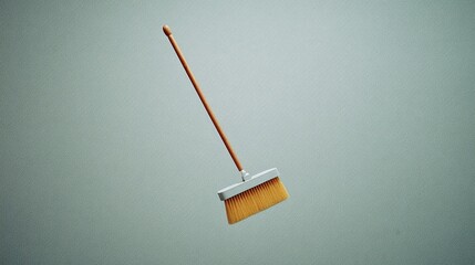 Minimalist Image of a Floating Wooden Broom on a Light Gray Background