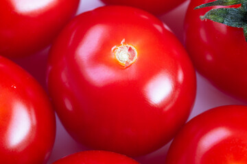 Close up glossy cherry tomato center, intense red sheen and mirrorlike skin, studiolit surface conveying premium culinary garnish, ideal for chef plating and gourmet food styling