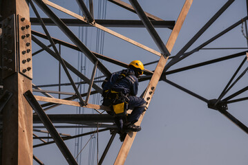 Electrical engineers climb high voltage power poles for maintenance.