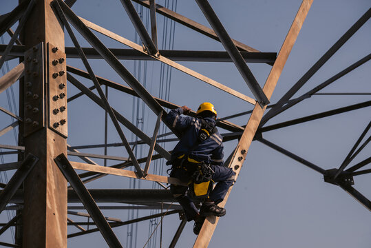 Electrical engineers climb high voltage power poles for maintenance.