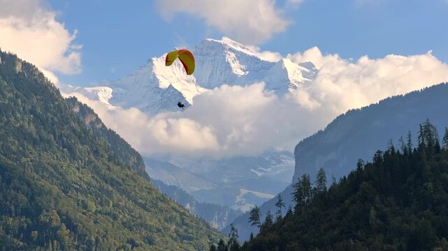 A paraglider flying in front of the Jungfrau mountain in Interlaken, Switzerland, with the majestic Alps in the background