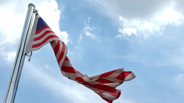 Malaysian flag waving in the wind against a blue sky