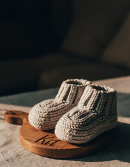 Baby name Kit engraved on a wooden plaque with knitted baby shoes. Image for baby name reveal