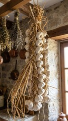 sunlit white garlic plait interwoven with golden straw hanging from wooden beams