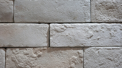 White brick wall with roughly surface. Building structure and interior decoration, background texture. Close-up.