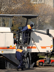 Asphalt removal using heavy machinery. Construction and repair of the road. Modern technology of laying a highway with a solid surface. People work at a construction site. Rolling asphalt