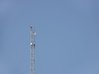 Radio-television tower for receiving and transmitting electromagnetic signals at a distance. Metal high-tech construction shrouded in a white cloud. The source of the pulse frequency